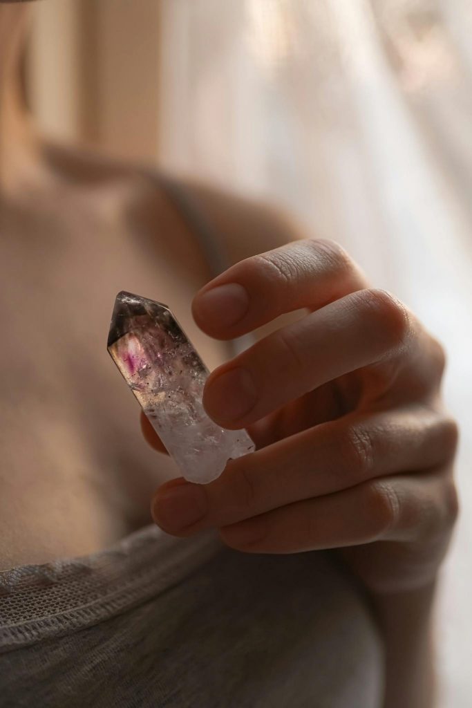 A close-up of a woman's hand holding a crystal, set against a soft and warm background in London.