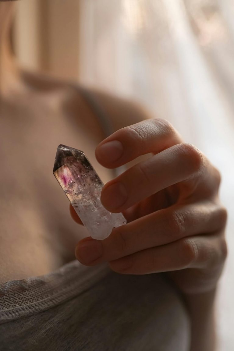 A close-up of a woman's hand holding a crystal, set against a soft and warm background in London.