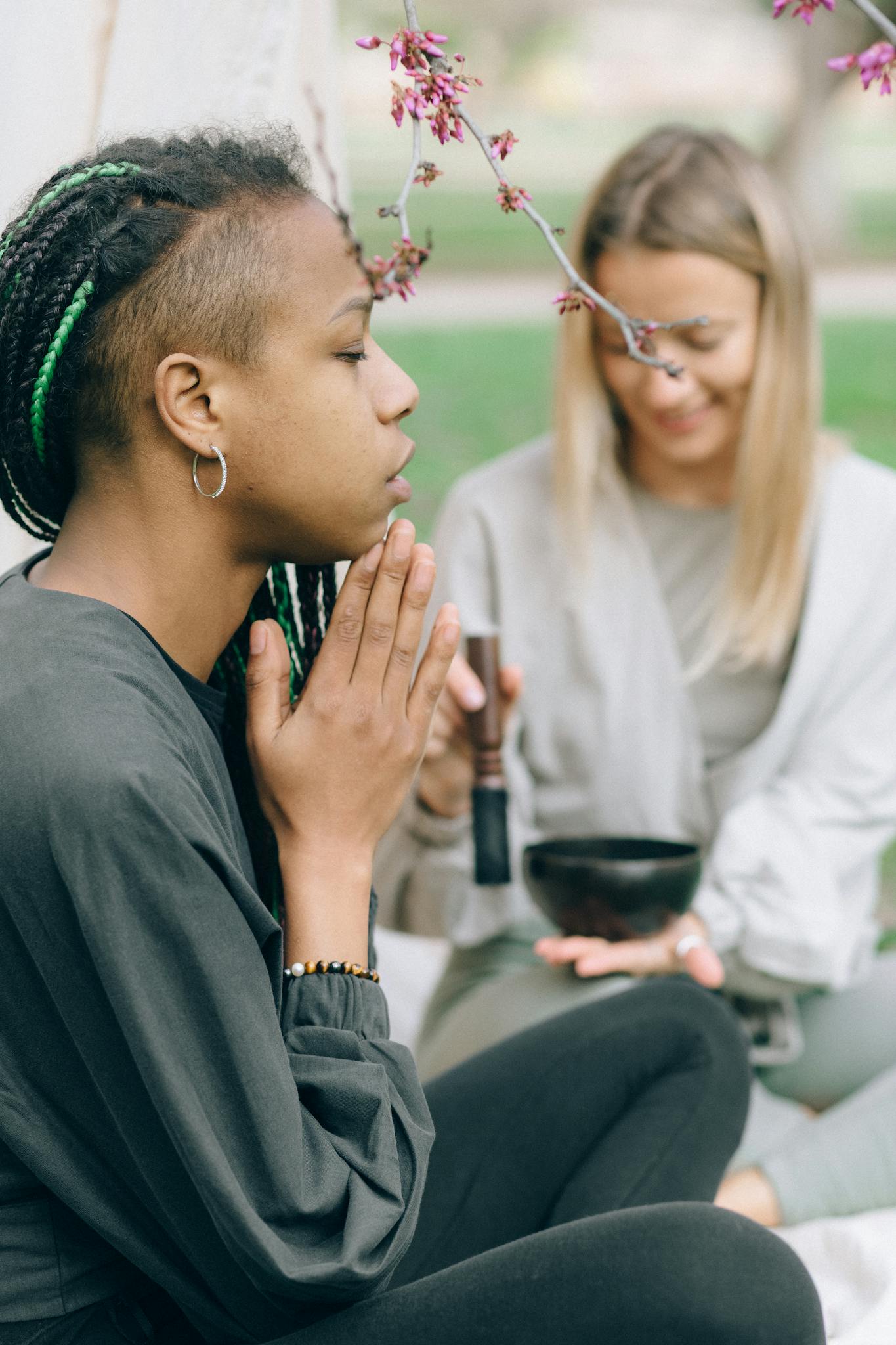 Two women meditating peacefully outdoors, engaged in a mindful practice.